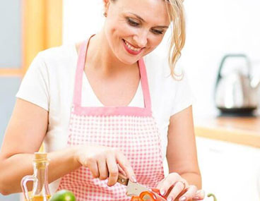 Cute woman cuts salad sitting